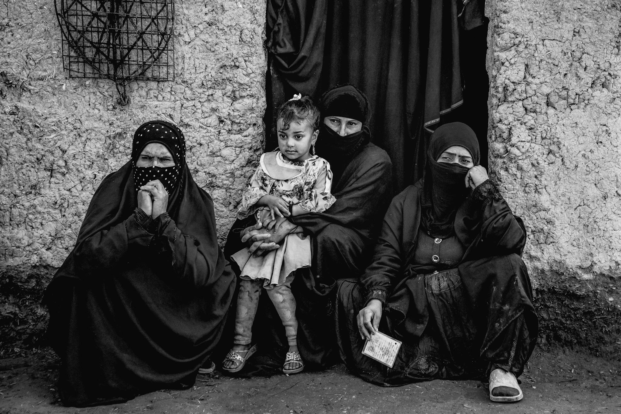A compelling black and white portrait of a Muslim family sitting together, highlighting cultural attire and expressions.