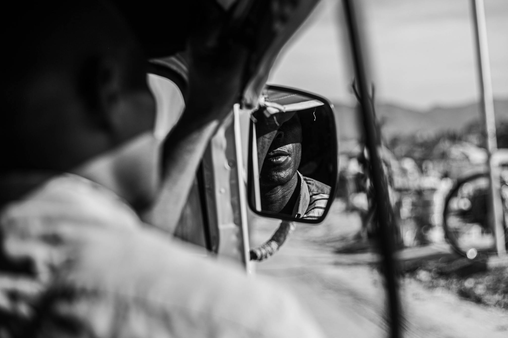 A contemplative black and white rearview mirror portrait reflecting deep thought
